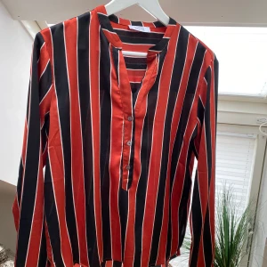 Randig Blus - Superfin blus i glatt material, lite längre bak. Nypris 500 kr. Köparen står för eventuell frakt, kan mötas i Göteborg/Kungsbacka. Storlek S. 