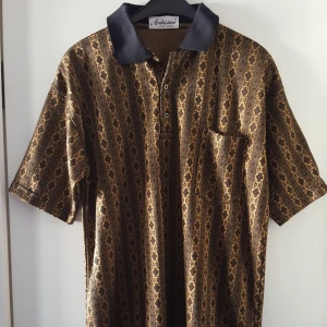  - Vintage mönstrad t-shirt, svart och lite lätt guldglittrig. Står inte storlek men uppskattar till ca M/L. Tycker även den sitter snyggt oversize på mindre storlekar. Fraktkostnad blir 56kr.