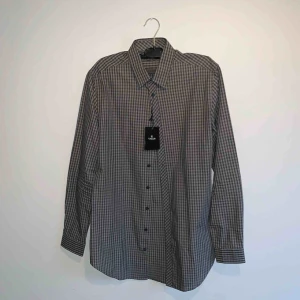 - Gråsvart slim fit / long line skjorta från Tiger Of Sweden. Aldrig använd endast provad med prislapp kvar på.  Skick 10 / 10. Ord pris 999kr.