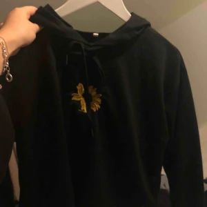  - Fin svart Hoodie med en solros på Köparen står för frakt 