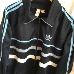  - Vintage adidas från 80-talet. Väl använt skick och en del mindre slitningar och ett litet hål  på en av armarna, (knappnålstort) Den rätta tunga 80-tals-looken 🔥. storlek 192 vilken motsvarar large / 