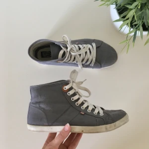 Converse-liknande skor - Gråa tygskor med vita snören. Använda ett fåtal gånger för ett par år sen men fortfarande bra skicka förrutom en liten repa på högra skon där snörerna slutar ~ frakt 70kr