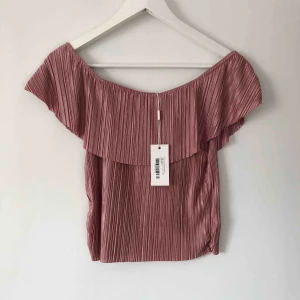 - Off shoulder topp med volang i jättefin rosa färg. Från Nicole Falcianis kollektion på Nelly. Helt oanvänd, prislappen kvar. 