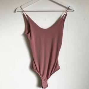  - Rosa body i jättefint stretchigt material. Låg i ryggen. Aldrig använd. Säljes då den inte kommer till användning.