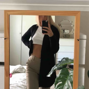  - Svart stickad cardigan med fickor, köparen står för frakten