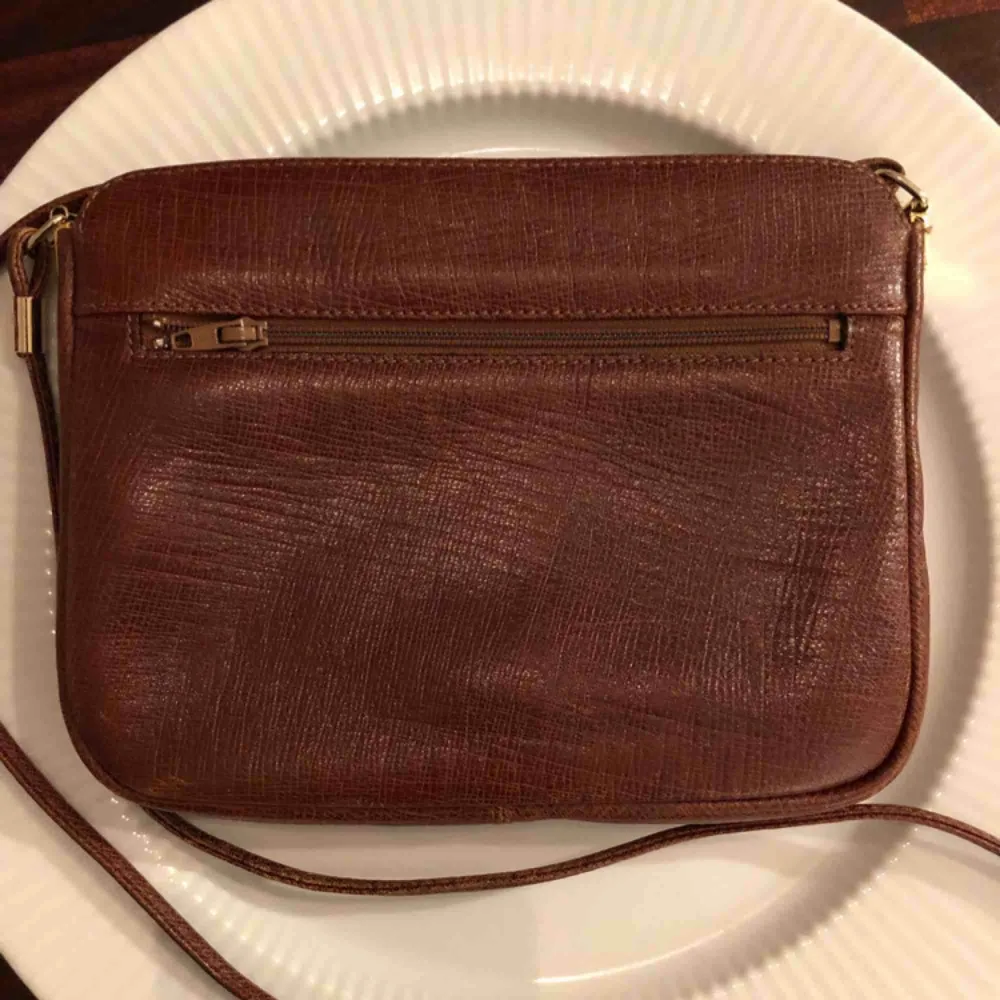 Vintage mindre handväska i brunt läder från Pourchet Paris (Made in France). Gulddetaljer och i fint skick!. Accessoarer.