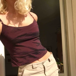  - 100% viskos. Vinröd med en mörk överton. Tröjan är köpt second hand på humana, funkar för mig som har 36, den går att ha tajt och dra åt band etc så kan tänka mig att det funkar för fler storlekar! 