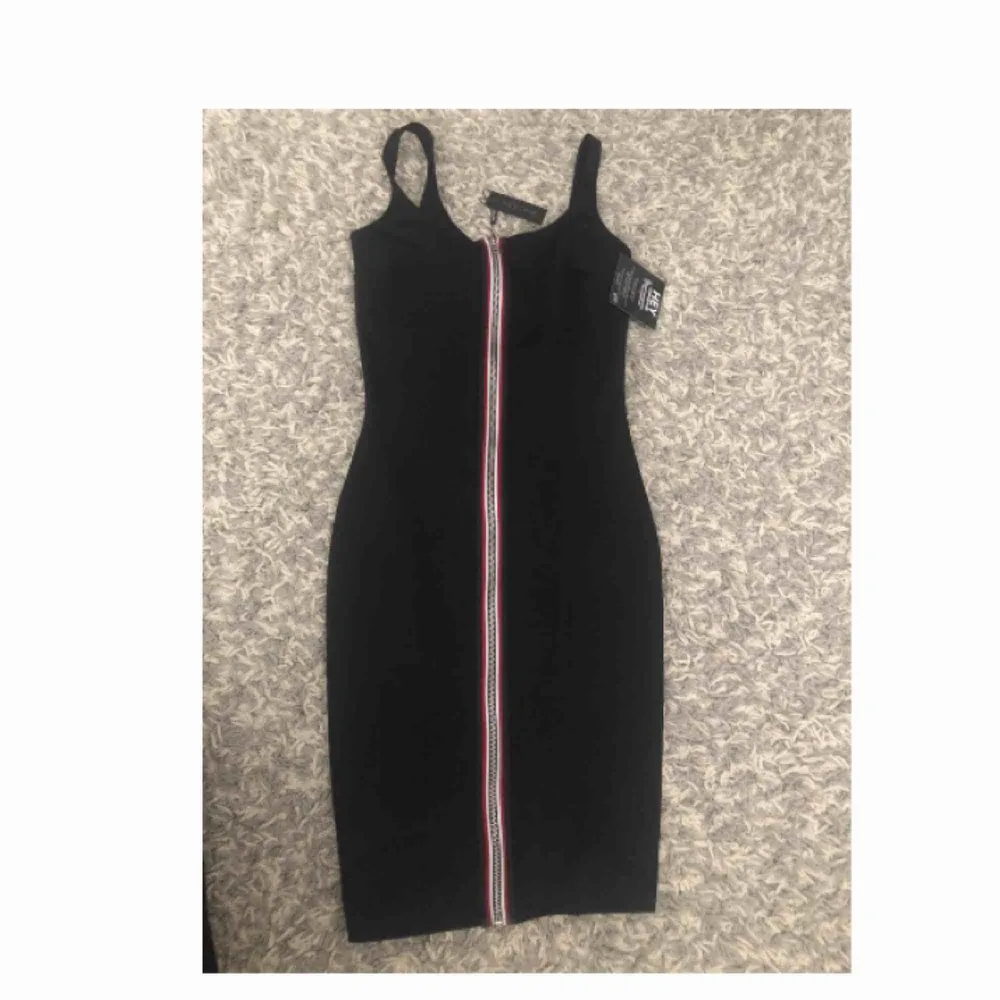 En svart klänning som är både stretchig och tajt i modellen. Klänningen har en dragkedja på framsidan som är en väldigt fin detalj! Klänningen är oanvänd då den är för liten för mig i bysten men längden är perfekt då jag är 162 cm!. Klänningar.
