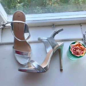  - Silvriga ormskinnsmönstrade klackskor från New Look. 10 cm klack. Aldrig använda, bara provade.  Kan mötas upp eller skicka för 70kr.😊