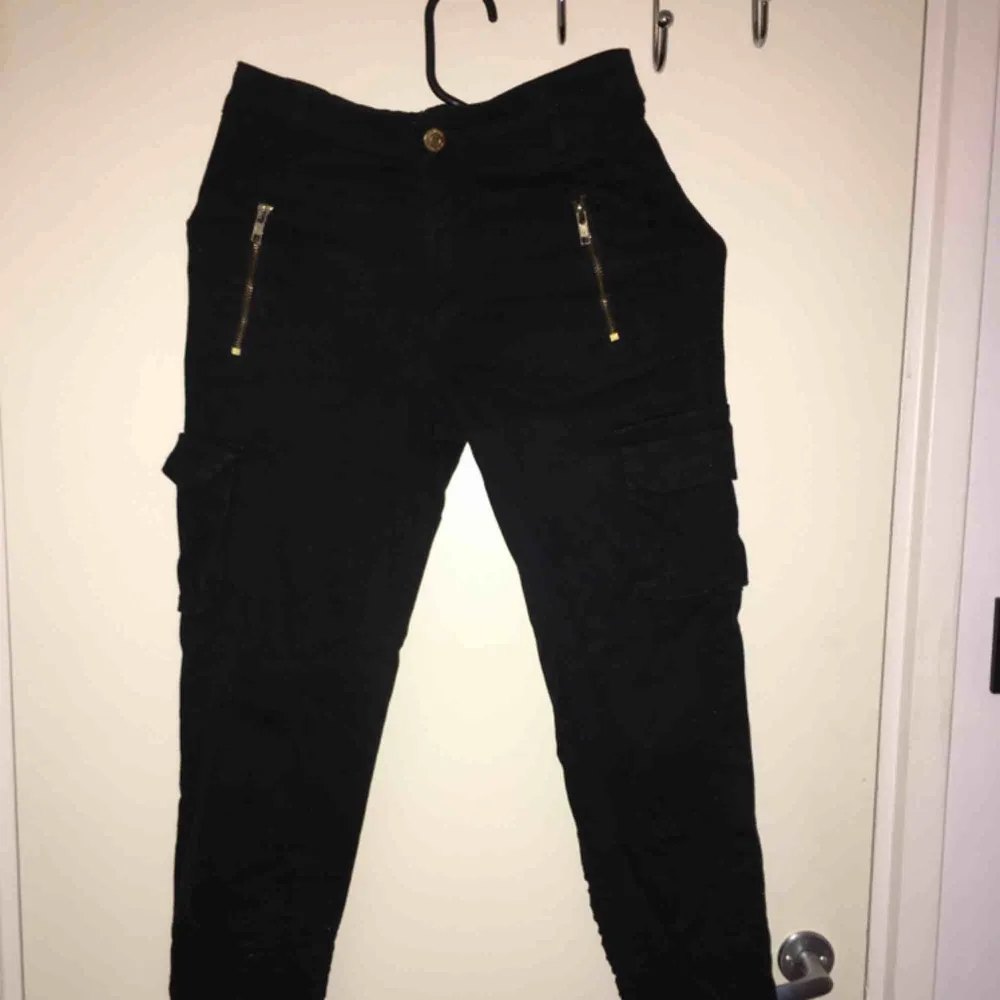 Svarta cargobyxor med hög midja, gulddragkedjoe och fickor på båda sidor. . Jeans & Byxor.