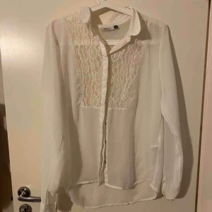  - Vit blus med spetsdetalj i bra skick! Ganska genomskinlig men så fin med spetsbh under