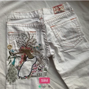Broderade true religion jeans - Jag säljer ett par sjukt fina vita truereligion jeans. Dom är utsvängda och lowwaist med ett asballt tryck på bak🦋 Köpte dom här på Plick men dom är tyvärr för små för mig. Dom är strl 26 men skulle säga att de passar en xxs💞 helt oanvända                   Köparen står för frakten