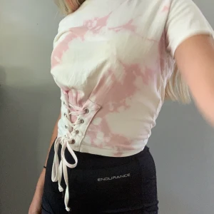 Tie dye T - 💗rosa o vit t-shirt med korsett detalj fram till, passar nog bäst på s om man vill ha den tajta effekten. Kan mötas i sthlm/Värmdö eller fraktas för 40kr💗