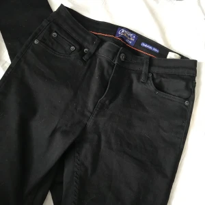 Jeans  - Ett par svarta jeans med hål vid knäna. Använda fåtalgånger och är i fint skick. Storlek 28 i midja och 30 i längd. Buda! Köparen står för frakten 