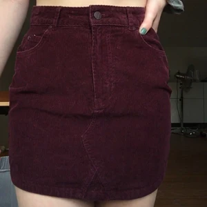 Vinröd kjol i manchestertyg - Jättefin vinröd kjol i manchestertyg från Carlings. Storlek S men passar även en mindre M. Har bältögglor vilket gör att du lätt kan spänna åt den mer i midjan med hjälp av bälte. Har även fickor både fram och bak