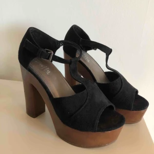  - Svarta Duffyklackar av mockaimitation med träklack. Storlek 37, använda ett fåtal gånger! Har lite slitningar i fram på platån men annars i gott skick. 