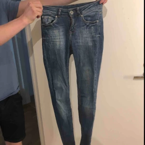  - Blå tighta jeans med lite slitningar i bra skick. 