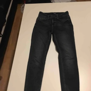  - Ett par mörkblåa jeans som nya med en dragkedja i bak av smalbenet