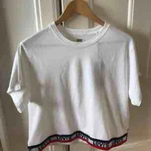  - Oversized t-shirt från Levi’s. Vit med en snygg Levi’s-text längst ner. Lite kortare i magen och stor i storlek. Riktigt snygg i sommar!🌞 Helt oanvänd med prislapp kvar. 