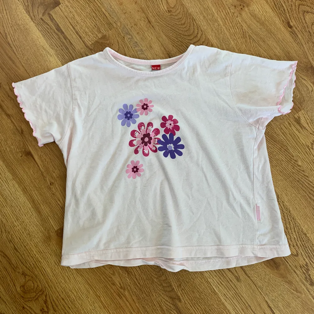 Rosa magtröja med motiv av blommor i olika färger. Perfekt skick. . T-shirts.