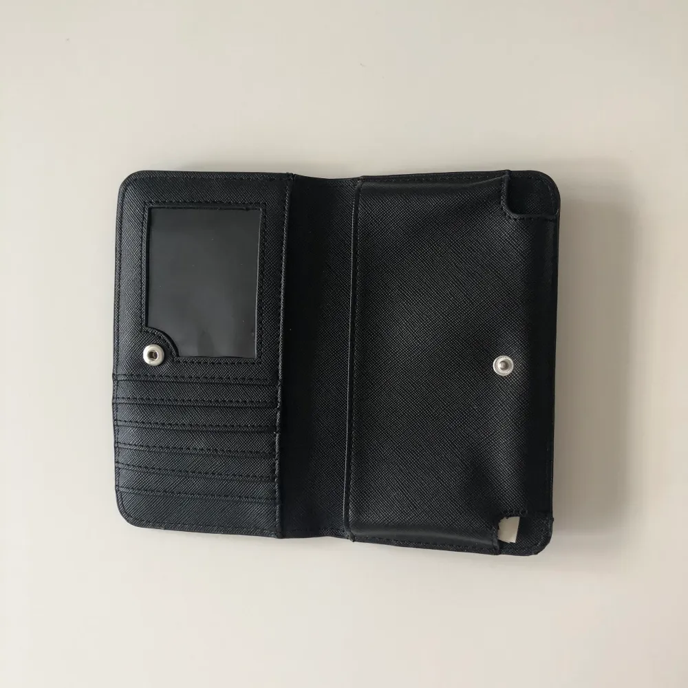 En svart plånbok med silverdetalj, där man även kan ha mobilen. Är i väldigt bra skick. OBS! passar ej för Iphone plus/max. Frakt tillkommer! . Väskor.
