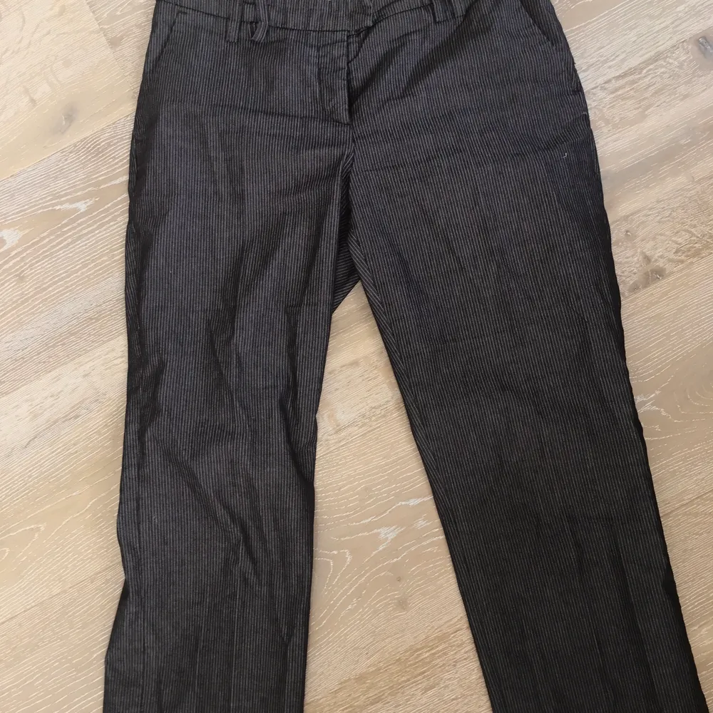 Mörkbruna randiga kostymbyxor som har avklippta ben och är lågmidjade.. Jeans & Byxor.