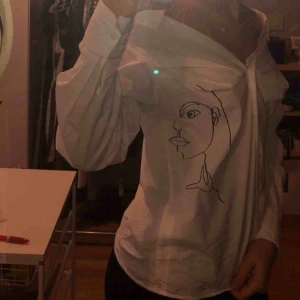  - Snygg blus från H&M med ett ansikte på vänster sida. Frakt är inräknat. Passar mig storleksmässigt och är 36 så passar det också.