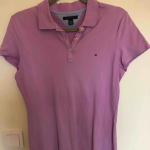  - Rosa/lila pikétröja från Tommy Hilfiger. Storlek L men är mer som en M. Passar även S. Använd ett fåtal gånger. Köparen står för fraktkostnad.  