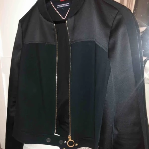 Tommy Hilfiger Jacka - Tommy Hilfiger jacka i jättebra skick! Den är mörkblå med svarta detaljer och guld kedja. Köptes förra året- har tyvärr växt ur den.