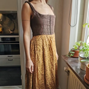 Klänning med korsett - Härlig klänning i vackra höstfärger, perfekt för oktoberfest eller med kängor stickade strumpor och kofta. Tror att det är en riktig traditionell schweizisk klänning med hyskor och hakar framtill. Jag är 165 och klänningen når mig 1dm under knät. Kan mötas upp i Gbg eller frakta (50kr)