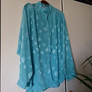 Vintageblus - Cool vintageblus i ljusblått, silkeslikt material. Passar de flesta storlekar beroende på hur man vill ha den. Snygg som oversize och/eller att ha nerstoppad i byxor. 