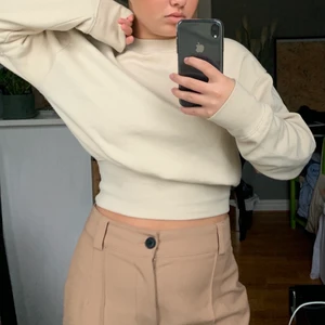 Beige cropt sweatshirt - En jättefin beige sweatshirt med mudd som man kan justera i valfri höjd. Knappt använd, bra skick. Superfin passform som kan framhäva former. Jättemysigt fleece material på insidan.  Frakt ligger på 63 om inte möte är aktuellt. 
