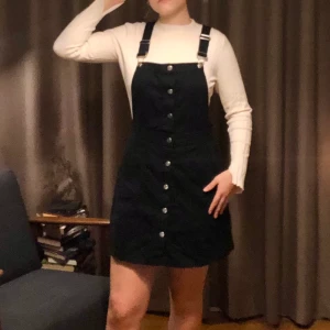 Svart hängselklänning - Säljer min fina hängselklänning! Knappt använd  då jag inte har kjol och klänningar så ofta. Kan stylas på så många olika sätt. Fint, svart jeanstyg och snygg A-linje skärning. Knäpps med silverknappar och har hängslen som går att knäppa av. Köpt på hm för 299kr. Skriv gärna vid frågor, eller om ni önskar fler bilder. Tvättas såklart innan den skickas!