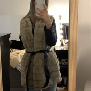 Fake päls väst strl 38 - Lila/beige fake päls väst med skärp till. Använd 2/3 gånger och som ny. Säljer för 200kr och kan mötas upp i Malmö💕