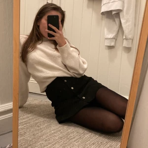 Kort svart kjol  - Kort svart skjol i mockaliknande material med knappar som ”håller ihop” kjolen. Väldigt skön och bra kvalite men använder den inte längre. Jag är 160 och petit i kroppen, kjolen är så lång som på bilderna. Köparen står för frakt (vet ej det fraktpriset ännu) 