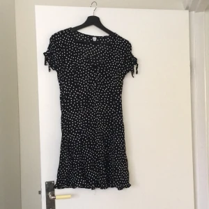 - Jättesöt kort prickig svart viskose klänning från Hm. Med knappar, smickrande skärning. Strl 42 men krympt i tvätten, mer som strl 38. Knappt använd, som ny