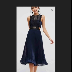  - Väldigt fin midiklänning, passar perfekt för bröllop och fest. Mörkblå med svarta virkade detaljer. Knäppning med dragkedja. Oanvänd med tagg kvar.  Nypris: 800kr *Obs! Första bilden är från hemsidan.