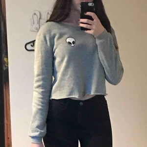  - Ljusgrå, croppad top med en liten alien på Jättesöt men säljer då jag sällan använder den Frakt ingår i prisen