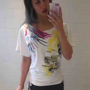  - T-shirt med färgstarkt tryck på framsidan och smickrande snörning på sidorna som man knyter. Den är i storlek ”M/L” men jag som har XS-S kan ha den så det beror på hur man vill att den ska sitta 💁🏻‍♀️💕☀️