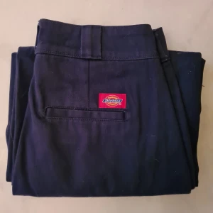Wide Leg Work pants by Dickies Girl stl 36 - Jättefina marinblåa vida byxor från Dickies. Har sytt upp dom i benen så dom passar någon som är 163cm eller någon lite kortare eller längre☆ Nästan aldrig använt så dom är i nyskick! Sitter som dom två andra bilderna fast dom är marinblåa. Frakten ingår inte. Tar swish :)