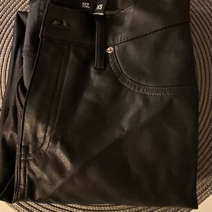 Jeans  - Jeans i ”läder” köpta på lager 157 aldrig använda men såg att en remsa där man stoppar i bältet va trasigt