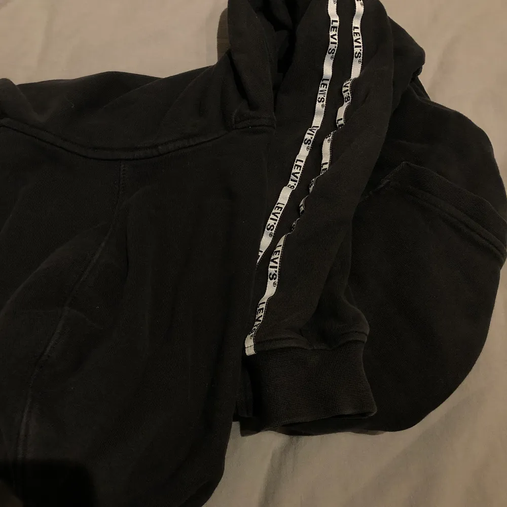 snygg levi’s hoodie som är svart med något ljusare detaljer vid sömmar osv (syns på bilderna). vita ränder på armarna med loggan på, en del använd men i väldigt fint skick! pris inklusive frakt🥰. Hoodies.