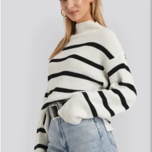 Randig stickad tröja - Säljer denna supermysiga stickade tröjan från Nakd! Den är vit och svartrandig och har lite högre hals. Det är som en slits på båda sidorna men de är lätta att stoppa ner så att de inte syns om man inte vill! Endast använd ett fåtal gånger! Nypris: 349kr