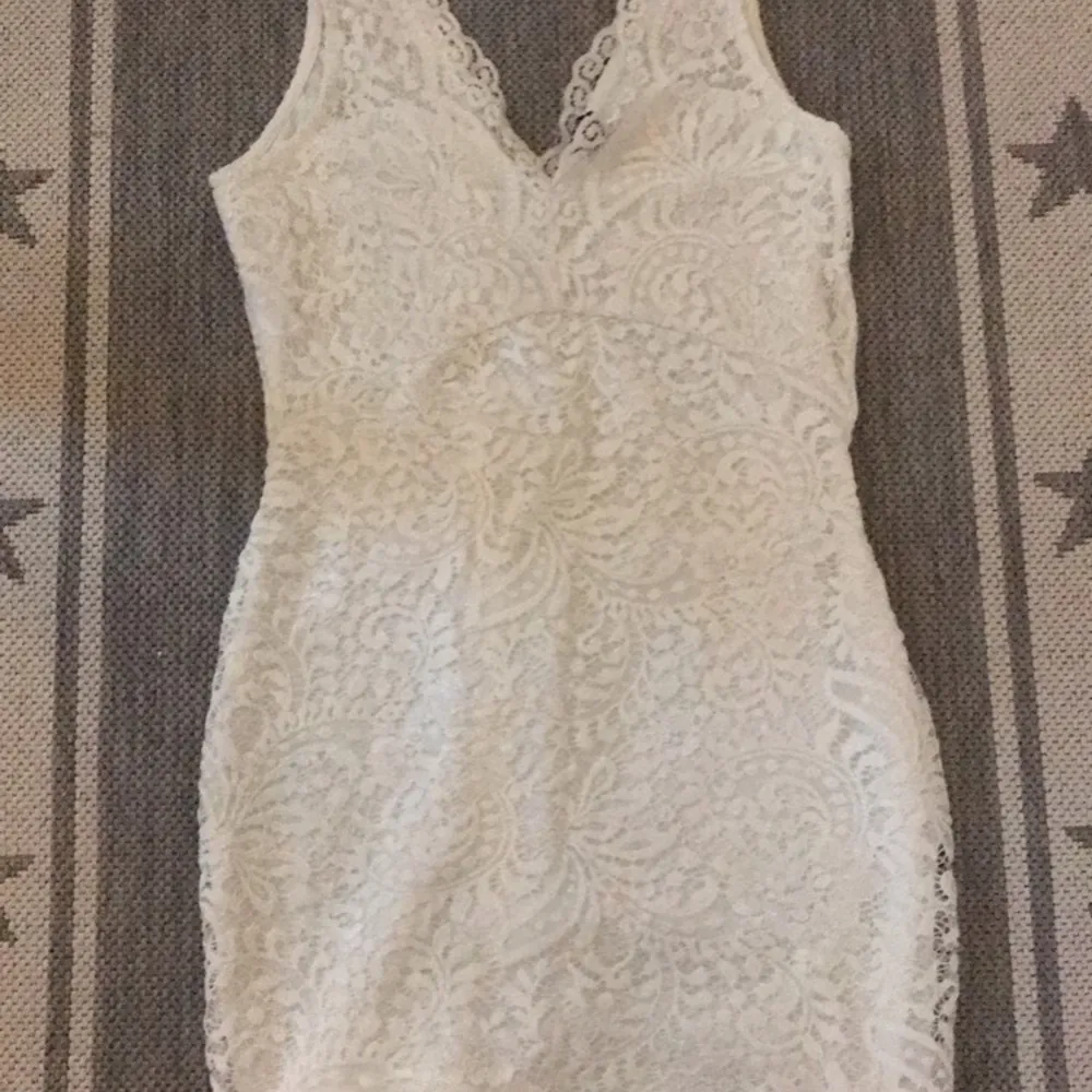 En vit spetsig klänning med en V ringning. Fint skick. Storlek S. Köpt på Vera Moda. . Klänningar.