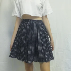 Prickig kjol  - En mörkblå veckad kjol med små vita prickar på. Den veckade detaljen får den att påminna om en tenniskjol. Materialet är tunt och i 100% polyester. Märket är okänt. Står ingen exakt storlek men uppskattar att den är S/M. Elastisk i midjan. Längd: 49,5 cm. Frakt tillkommer. 