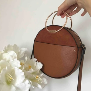  - En snygg och rund väska med guldiga handtag och faux mocka detaljer.   Köptes på H&M men aldrig använd.  Perfekt till sommaren och festivaler!   200 kr  Köparen står för frakten  Möts upp Göteborg 