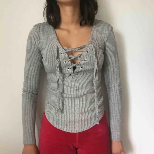  - En grå tröja som är ribbad med snörning över bröstet. Kommer från Gina Tricot och kostar 100kr inklusive frakt.