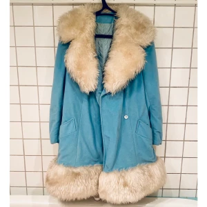 Ljusblå kappa - Underbar! Går nedanför stussen. Ej äkta päls. Innefodret behöver lagas vid armhålor. 