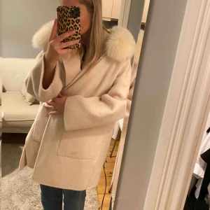  - Superfin kappa ifrån born in Stockholm. Cashmere / ullblandning, nypris 4900 kr,den har en liten fläck som syns på ena bilden, samt att de som håller bandet på ena sidan har lossnat halvt, men går lätt att fixa! äkta pälskrage. Fint skick 
