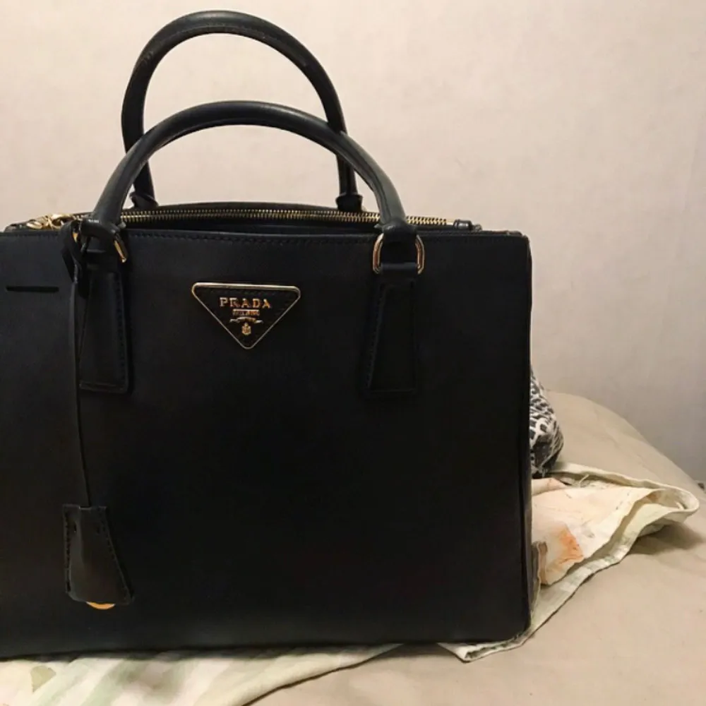 Svart Prada saffiano väska i läder. En riktigt elegant lyxig väska. Köpt för 3200kr. Först till kvarn. För mer detaljer skicka ett meddelande. . Väskor.